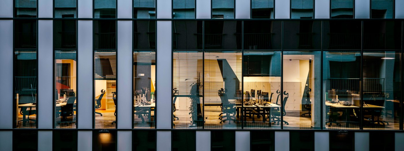 Lit office interiors seen through a glass facade at night