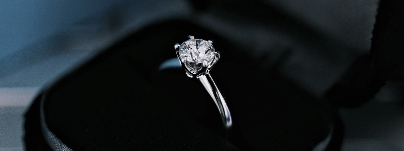 A solitaire diamond ring on a dark surface